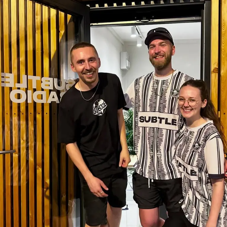 three people from subtle radio smiling at the camera