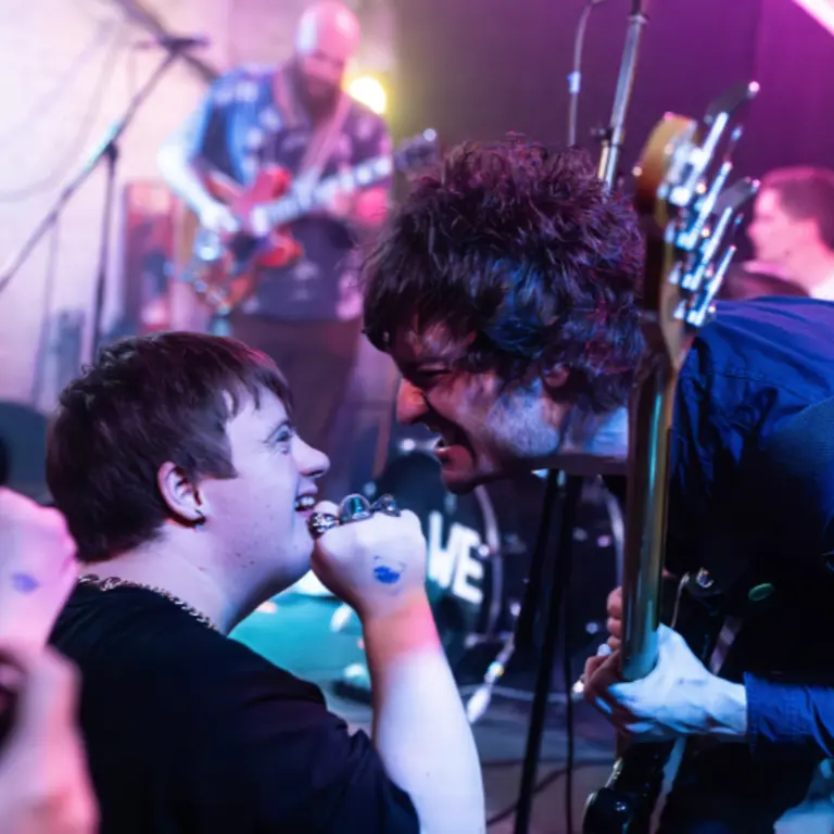 a musician sings to an audience member, both smiling