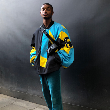 young person wearing a blue jacket against a black background