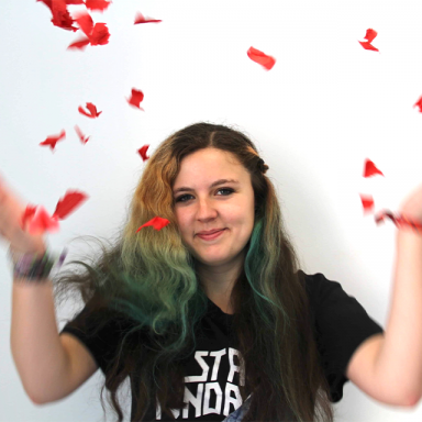 person with blue dip-dyed hair throwing rose petals in the air