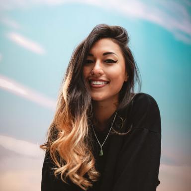 Woman with black and blonde ombré style hair wearing black jumper smiles at camera