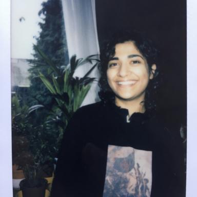 polaroid photo of rizmi smiling next to some plants